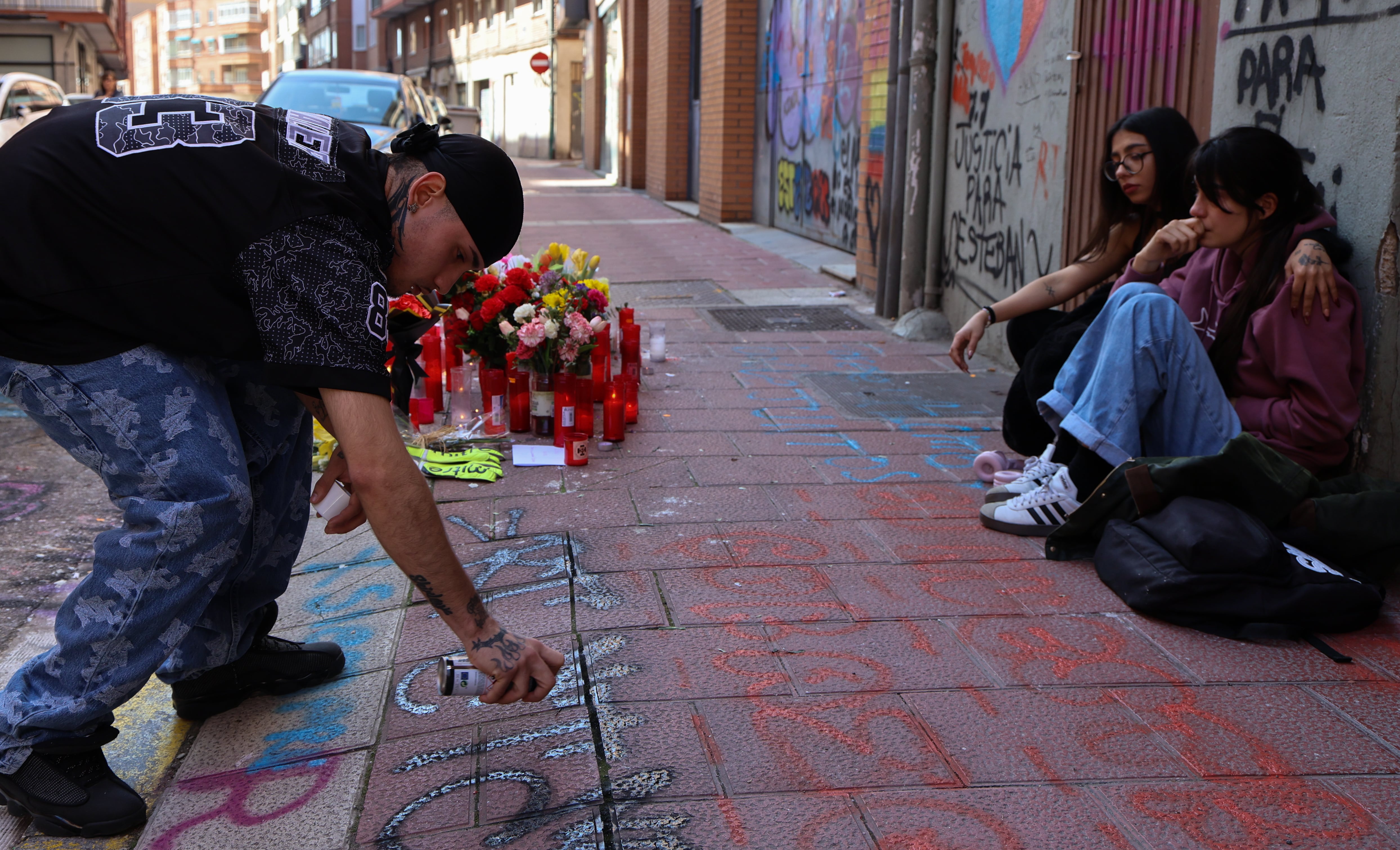 Mercy pinta un graffiti en memoria de Esteban, mientras una chica consuela a Natalia, en la calle Democracia, este jueves. 