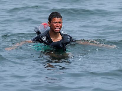 A Moroccan boy cries as he swims using bottles as a float, near the fence between the Spanish-Moroccan border, after thousands of migrants swam across the border, in Ceuta, Spain, May 19, 2021. Picture taken May 19, 2021. REUTERS/Jon Nazca