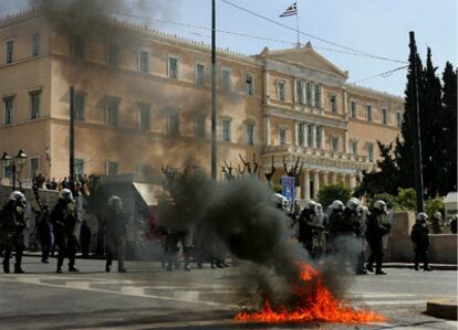 Agentes antidisturbios hacen guardia frente al Parlamento griego ante el fuego de un cóctel molotov el 11 de marzo de 2010