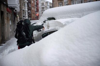 A man clears snow off his car in the Cántabra de Reinosa locality, February 3, 2018.