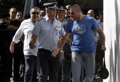 El diputado de Aurora Dorada Nikolaos Mihos (R) discute con un agente a su llegada a la sede de la policía griega en Atenas.