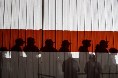 Varias sombras de asistentes se proyectan sobre una pared durante un mitin del presidente de los Estados Unidos y candidato a la reelección, Donald Trump, en el aeropuerto Toledo Express de Swanton, Ohio.