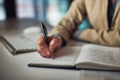 Un hombre toma notas en un cuaderno.