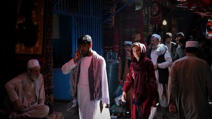 Uma mulher caminha entre homens pelas ruas do bazar Mandawi, em Cabul.