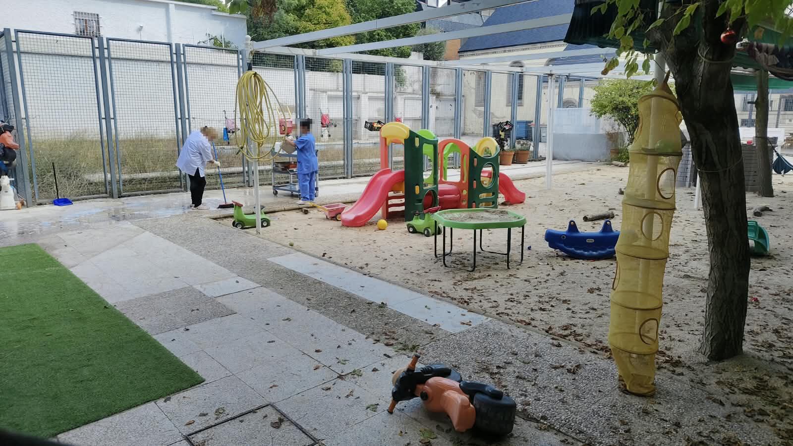 
Dos trabajadoras de la limpieza friegan los platos en el patio de la escuela.