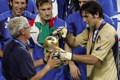 El portero de la selección italiana Gianluigi Buffon cede el trofeo al técnico italiano Marcello Lippi ante la atenta mirada de Totti y de otros jugadores italianos, tras su victoria en la final del Mundial.