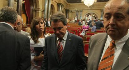Artur Mas (c), entre Alicia Sánchez-Camacho (PP) y el consejero de Interior, Felip Puig, en el Parlamento catalán, mientras cientos de indignados se manifestaban en el exterior.
