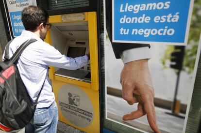 Un usuari retira efectiu d'un caixer de CaixaBank.