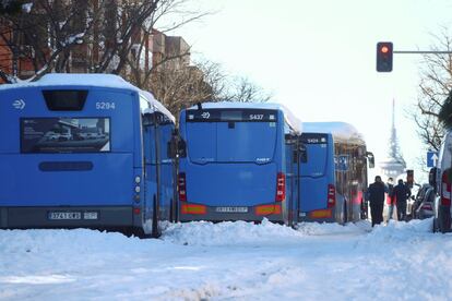 Varios autobuses municipales atrapados en la capital madrileña, este lunes. Al fondo, el Pirulí.