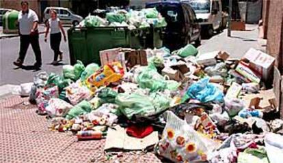 Dos vecinos de Almería rodean la basura acumulada en las aceras durante tres días de huelga del servicio de recogida de desechos.