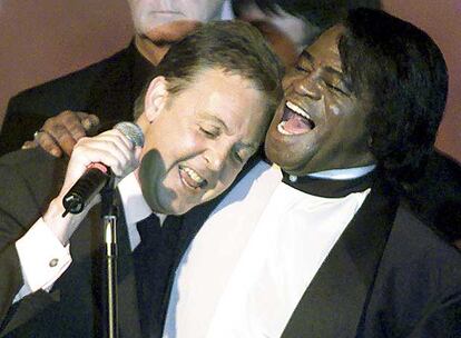 James Brown comparte micrófono y escenario con el ex <i>beatle</i> Paul McCartney, en un acto en el que ambos coincidieron en Nueva York, en junio de 2000. Brown soñaba con profesionalizarse como boxeador o <i>pitcher</i> de béisbol. Pero entró en la música gracias al pianista Bobby Byrd, cuya familia prometió alejarle de la delincuencia.