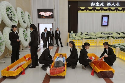 Un hombre 'yace' en un ataúd durante la simulación de un funeral para promover la festividad de Qingmingo o Día de los Muertos, en una funeraria en Jinhua, provincia de Zhejiang (China).