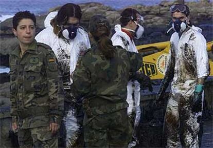 Dos militares junto a tres voluntarios en tareas de limpieza, en la playa de Muxía.