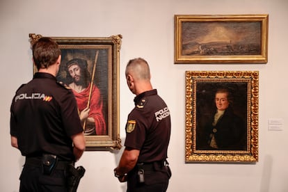 Dos agentes de la Policía Nacional contemplan tres obras de arte falsas incautadas en una operación en Valencia, en 2023.