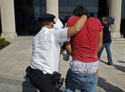 Un policía conduce a uno de los detenidos en los disturbios de Pozuelo de Alarcón a un juzgado de la localidad.