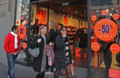 Varias personas con compras pasan ante una tienda con rebajas en Barcelona. EFE/Archivo