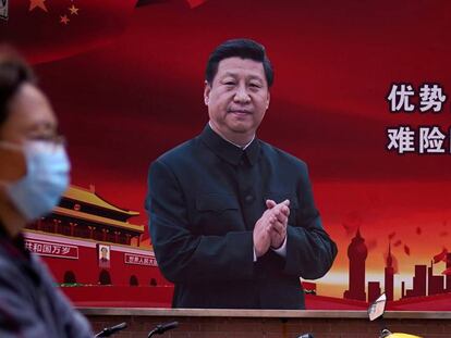 Una mujer pasa frente a un cartel con la imagen de Xi Jinping en Shanghái.