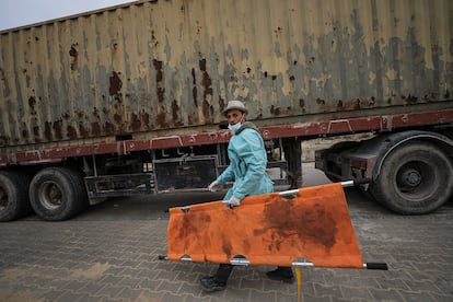 Un trabajador transporta una camilla durante la descarga de 111 cadáveres palestinos para ser enterrados en una fosa común, cavada este miércoles en el cementerio de Jan Yunis. 