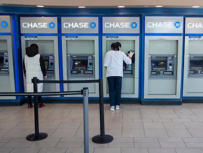 A worker cleans an ATM as a customer uses another at a Chase branch in the Queens borough of New York on March 24, 2020.