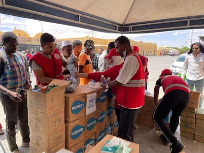 Un grupo de sudaneses recibe agua y comida de ACNUR en el puesto fronterizo de Qostol, entre Sudán y Egipto.