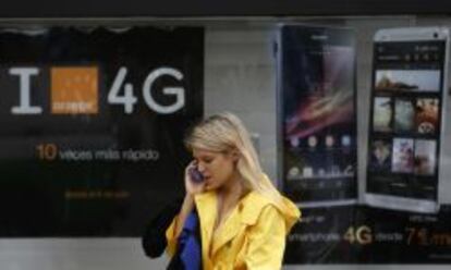 Mujer hablando por tel&eacute;fono frente a un cartel publicitario de Orange.