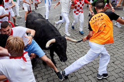 Los mozos se apartan al paso de uno de los toros de la ganadería Puerto de San Lorenzo, este domingo, durante los sanfermines de 2019.