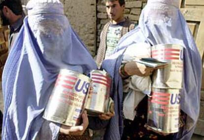 Dos mujeres afganas recogen en Kabul botes de aceite que forman parte del programa alimenticio de la ONU.