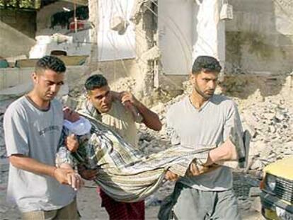 Tres palestinos trasladan a una mujer desmayada tras la demolición ayer de una casa de un miliciano en Yenín.