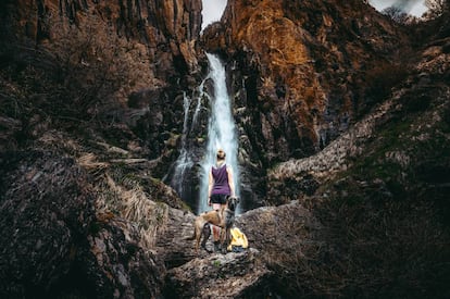 Una joven con su mascota junto a una cascada en la provincia de Palencia.