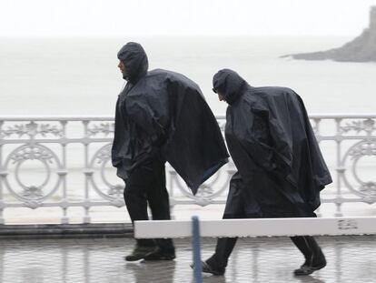 Dos paseantes por San Sebastián bajo los efectos de una fuerte lluvia.