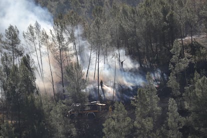 Varios bomberos trabajan en la extinción de uno de los focos del incendio cerca de la aldea de Los Peirós, en Teruel, este domingo.