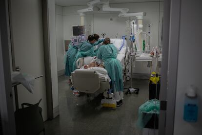 Sanitarias visitan a un enfermo en la UCI del Hospital de la Santa Creu i Sant Pau.