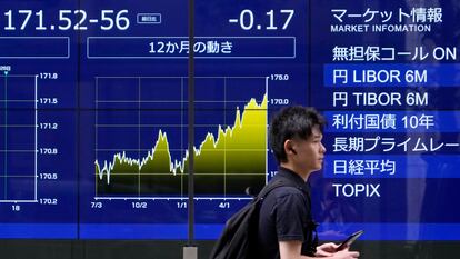 Un viandante pasa delante de un panel que indica la cotización del yen frente al dólar