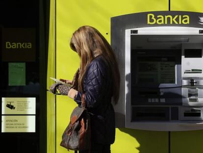 Una mujer, junto a un cajero de Bankia.