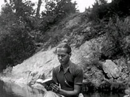 El poeta Luis Cernuda lee un libro sentado en una piedra en la orilla de un río. PLANO CONJUNTO - ESCENA