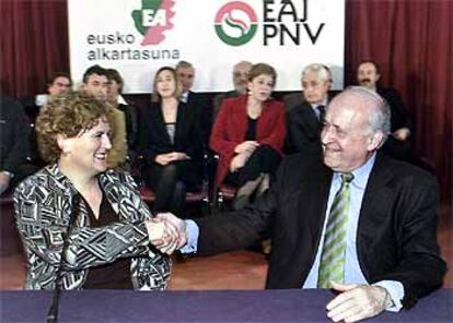 Begoña Errazti, presidenta de EA, estrecha la mano del líder del PNV, Xabier Arzalluz, tras firmar el pacto.