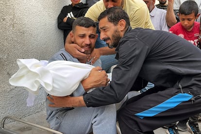 Dos hombres abrazan el cadáver de una víctima de los bombardeos israelíes en Gaza, el pasado lunes.