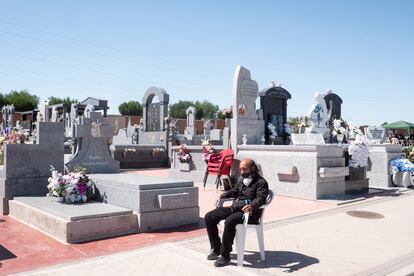 David Bizárraga sentado frente a la tumba de su padre a la que acude todos los días, en el Cementerio de Carabanchel, Madrid, en junio.