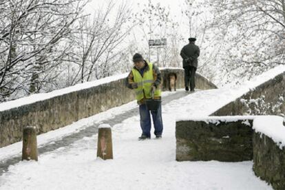 Un hombre esparce sal sobre la nieve en el puente románico de la Magdalena en Pamplona.