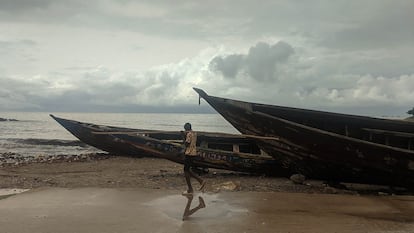 A resident walks past fishing boats on the coast of Conakry, Guinea.