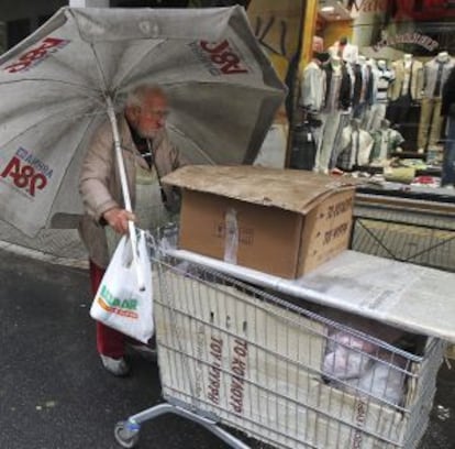 Un vendedor callejero empuja su carrito bajo la lluvia en Atenas.