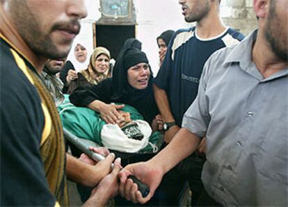 Miembros de la familia Al Hajin, atacada con obuses cargados de dardos el pasado miércoles en Gaza, entierran el cadáver de uno de los adolescentes.