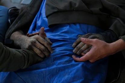 Dos palestinos sostienen las manos de su familiar muerto en un ataque aéreo del ejército israelí, en el Hospital Shifa en la Ciudad de Gaza. 