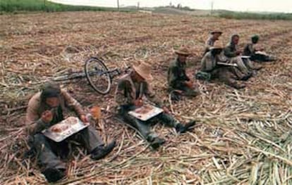 Cortadores de caña hacen un descanso para comer en una plantación cubana.