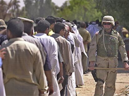 Un soldado estadounidense vigila que se respete el turno en una fila de ex soldados iraquíes que esperan para cobrar sus sueldos, en Bagdad.