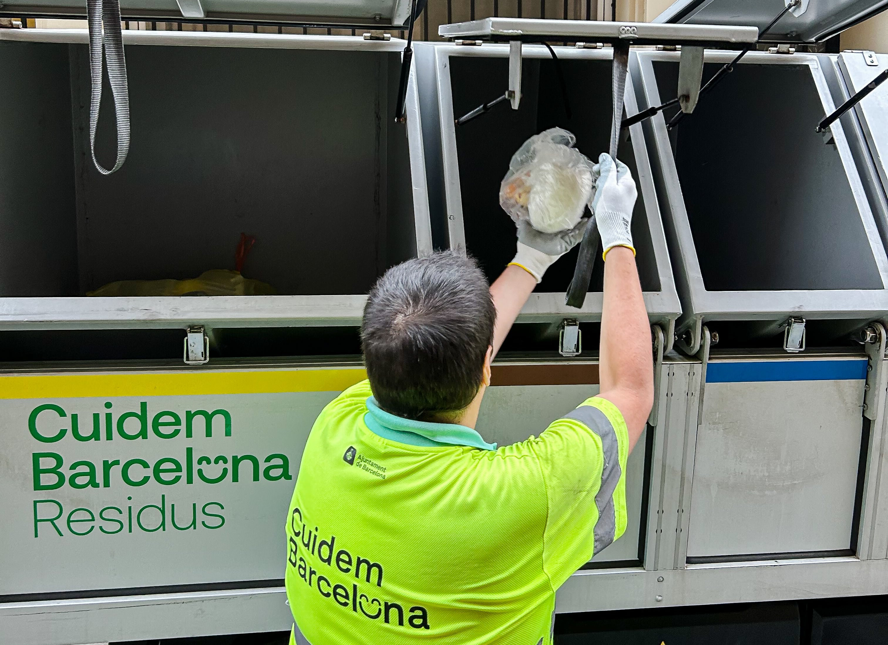 Un trabajador de la limpieza de Barcelona arroja residuos orgánicos en el depósito correspondiente del camión.