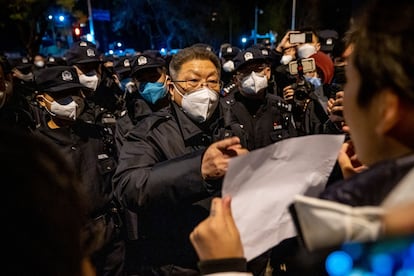 Un policía local habla con uno de los protestantes, que sujeta una de las características hojas en blanco, el pasado lunes en Pekín. Algunos jóvenes que participaron en las protestas de la capital han sido contactados por la policía y amenazados con ser detenidos.