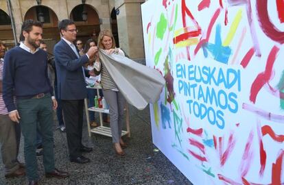 Sémper, Basagoiti y Quiroga descubren un eslogan en la plaza de la Constitución donostiarra.