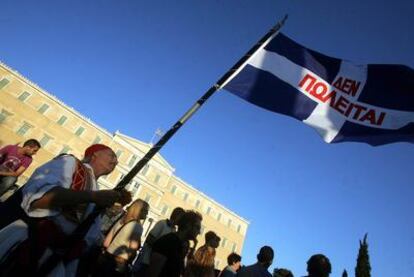 Manifestantes ondean una bandera griega que dice: "No en venta", en una protesta ayer contras las medidas de austeridad ante el Parlamento.