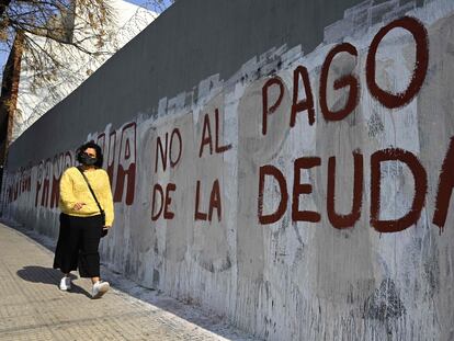 Una mujer pasa frente a una pintada contra el pago de la deuda, en Buenos Aires.